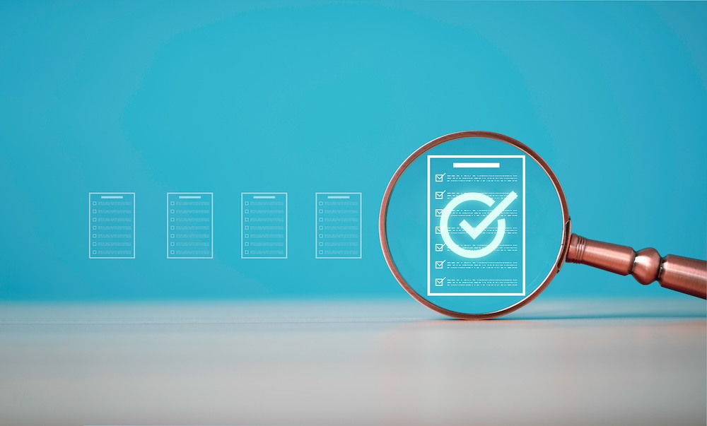 Magnifying glass reviewing a checklist representing CMMC compliance assessment